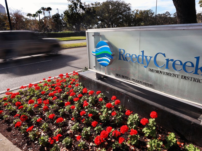 A car drives passed a sign with flowers planted in front at the entrance to Walt Disney World's Reedy Creek Improvement District headquarters in Lake Buena Vista.